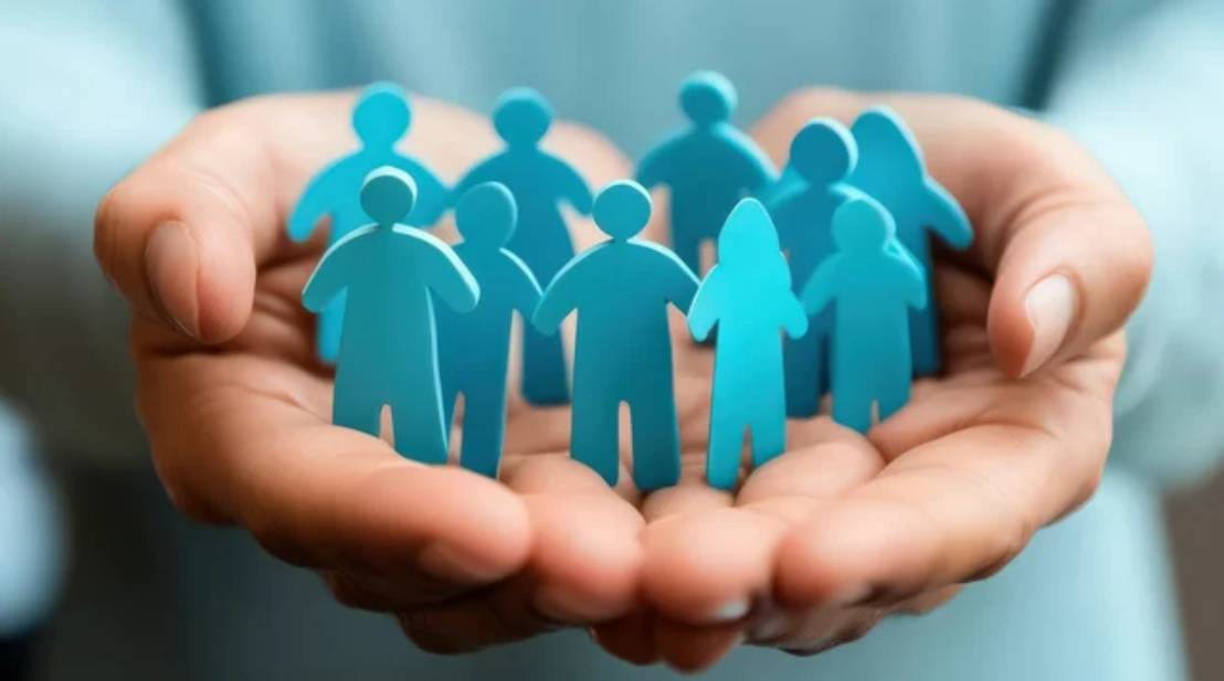 Hände halten blaue Papierfiguren, die ein Team symbolisieren