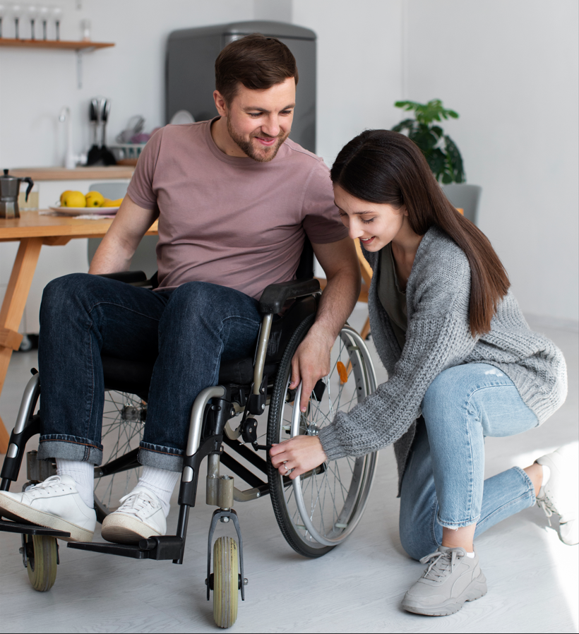 Eine junge Frau hilft einem Mann im Rollstuhl in einer modernen Wohnung